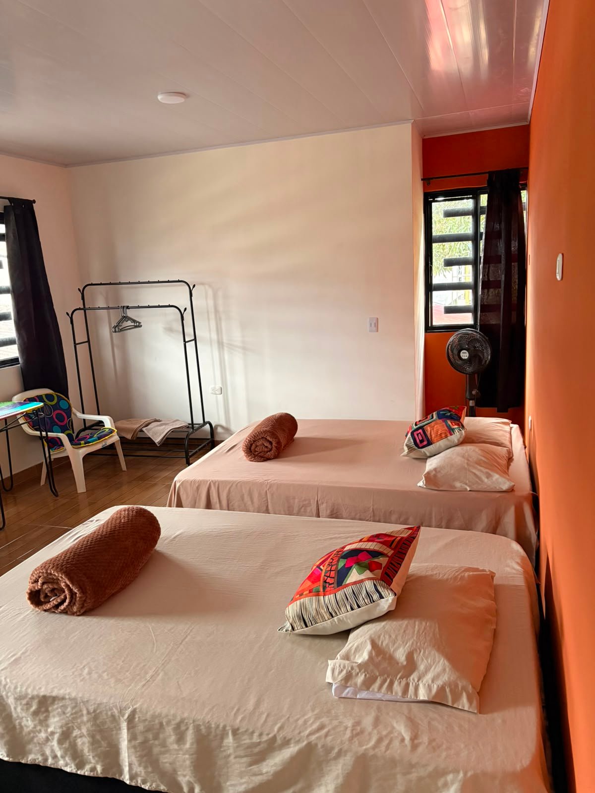 Embrujo: dos camas, mesa, sillas y ventilador, junto a ventana con cortina blackout