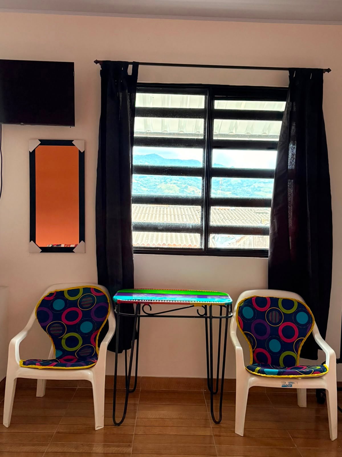 Vista a las montañas de Acacías desde la ventana del apartaestudio Embrujo, con mesa y sillas junto a la ventana
