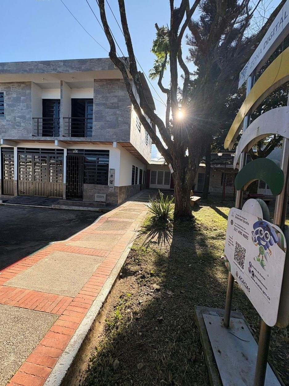 Entrada de Floral Home Acacías desde el andén del parque, entre los árboles